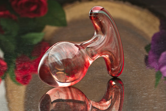 A glass butt plug made with glittering brassy-red glass and a comfortable T base